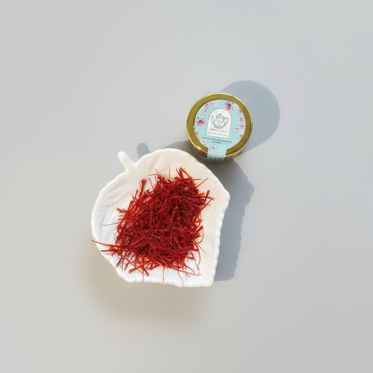 Premium Kashmir saffron threads in a white ceramic dish next to a small labeled jar